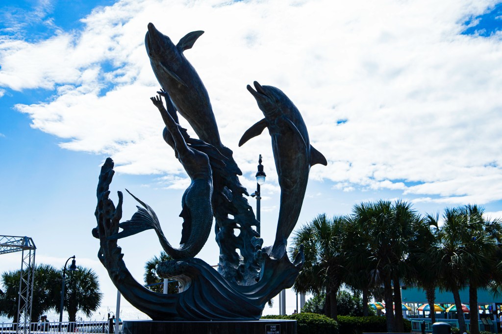 Statue of two dolphins and a boat in the water